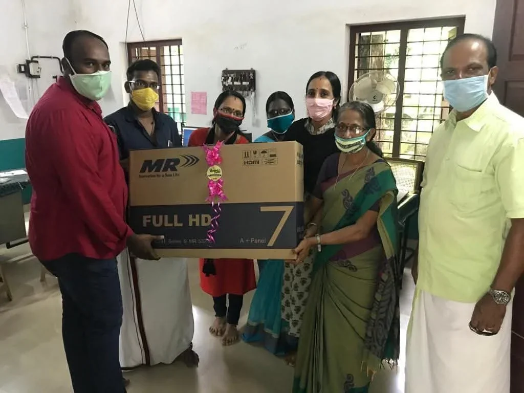 Alumni presenting a donated television to school teachers and staff at GVHSS Puthenchira